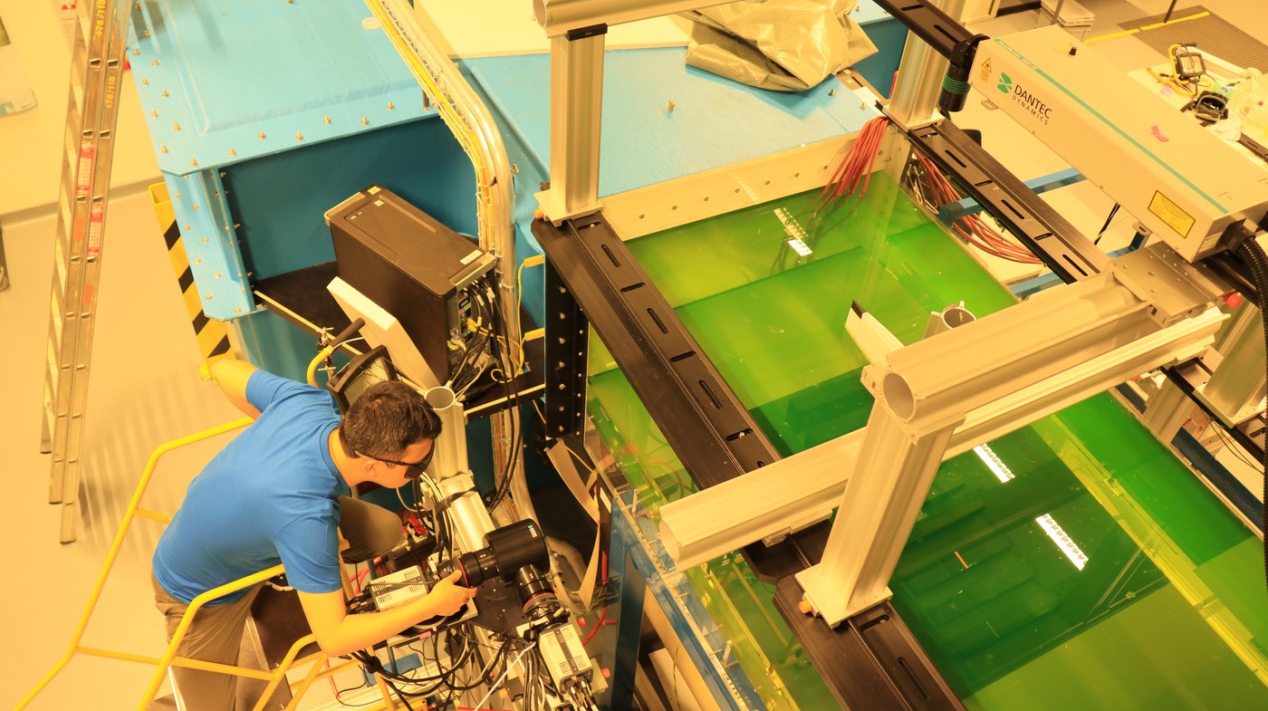 Researcher setting up PIV cameras beside the water tunnel with fluorescent dye